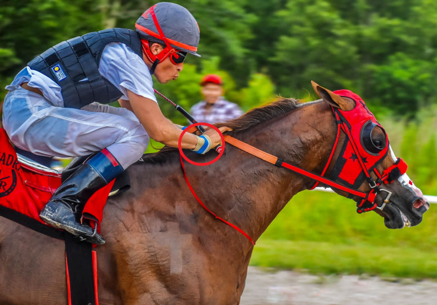 Jockey riding horse and red circle emphasizing shock devices on his wrist